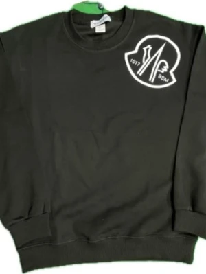 Moncler sweatshirt - Cool svart sweatshirt från Moncler med vit logga på bröstet och en liten patch på ärmen. Tröjan har rund hals, ribbade muddar och är gjord i mjukt bomullsmaterial. Perfekt för en avslappnad streetwear-look.