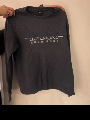 Mörkblå sweatshirt från Hugo Boss - en fin tröja från hugo boss som är i väldigt bra skick pris kan diskuteras bara att skicka iväg ett bud. storlek s/m