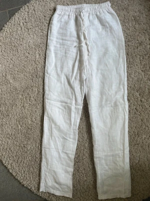 Vita linnebyxor  - Säljer ett par vita linnebyxor, med avslappnad passform och resår i midjan, från design by si. Perfekt till sommaren🩷