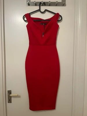 Röd v-ringad klänning Boohoo - Snygg röd klänning från Boohoo med v-ringning och figurnära passform. Klänningen är ärmlös och har en elegant, midilång siluett som framhäver formerna. Perfekt för dig som vill sticka ut med en klassisk men trendig look.