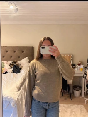 Beige stickad tröja med rund hals - Säljer en enkel och snygg beige stickad tröja med rund hals och ribbade muddar vid ärmslut och nederkant. Tröjan har en avslappnad passform och är perfekt att matcha med jeans. Materialet känns mjukt och skönt mot huden.