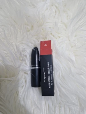 MAC Matte Lipstick Chili röd - MAC Matte Lipstick i nyansen Chili, en djup röd färg med varma undertoner. Läppstiftet har en klassisk svart hylsa med silverdetaljer och kommer i originalförpackning. Formulan är matt och ger ett intensivt färgresultat som håller länge.