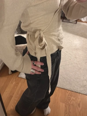 Beige omlottkofta från VILA - Säljer en beige omlottkofta från VILA i storlek XS. Koftan har långa ärmar, knytband i midjan och är stickad i ett mjukt material. Perfekt för lager-på-lager och enkel att styla till olika outfits. Passar jätte bra med ett par jeans. 