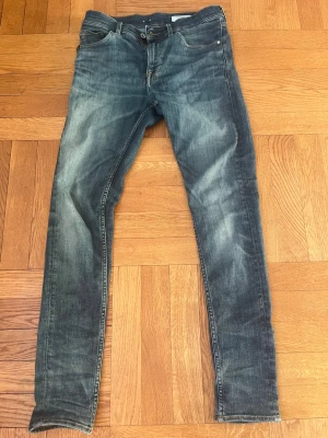 Blå slim fit jeans från Tiger of Sweden - Snygga blåa slim fit jeans från Tiger of Sweden med klassisk femficksmodell, storlek 28/32. Jeansen har en tvättad look med ljusa slitningar och har en skön passform. Ändå defekten är lädermärket på baksidan är lite slitet (se bild 4)
