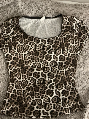 Leopardmönstrad topp från Stories - Säljer en snygg leopardmönstrad topp från Stories i storlek S (36-38). Toppen har korta ärmar, rund halsringning och är i ett stretchigt material som sitter tight.