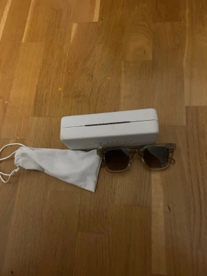 Transparenta solglasögon från Chimi - Säljer ett par stilrena solglasögon från Chimi med transparent, fyrkantig båge och bruna glas. Kommer med vit hård förvaringsbox och vit tygpåse. Perfekta för dig som vill ha en clean och modern look.