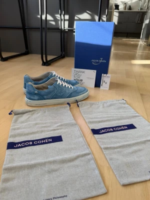 Jacob Cohën skor - Dom Snyggaste och mest unika skorna på marknaden. Jacob Cohën i modellen Dreamer. Skorna har en låg silhuett, vita snören och diskret logga på sidan. Ovandelen är i mjuk mocka och sulan är vit med märkets namn tryckt på sidan. Perfekta för dig som vill ha en clean och stilren look. Perfekt inför vår sommar. Sjukt svåra att få tag på. Skicket är 11/10.