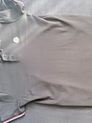 Svart pikétröja från Moncler - Snygg svart pikétröja från Moncler med klassisk krage och knappslå. Tröjan har Moncler-logga på bröstet. Nästan helt ny och inga skador eller något på den. Om ni har några frågor eller pris förslag så är det bara att skriva.