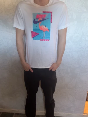 Vit Nike t-shirt med flamingotryck - Säljer en vit t-shirt från Nike, använt några gånger och den är i väldigt bra skick. 