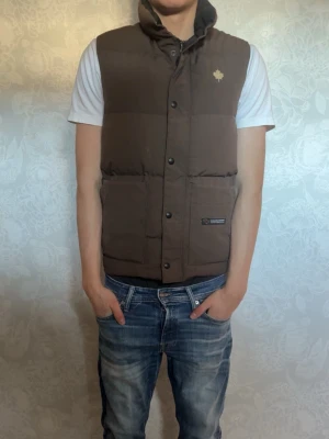 Brun dunväst från Canada Goose - Snygg brun väst från Canada Goose. Storlek XS, men funkar perfekt för mig som bär mästadels S eller M