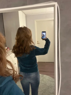 Blå velour hoodie med dragkedja - Snygg blå hoodie i mjuk velour med dragkedja framtill och huva. Modellen har ribbade muddar vid ärmslut och nederkant, perfekt för en avslappnad och trendig look. Passar till både jeans och mjukisbyxor för en chill stil.