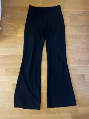 Svarta utsvängda kostymbyxor  - Säljer ett par svarta kostymbyxor från pull & bear med utsvängda ben och hög midja. Byxorna har hällor för skärp och klassisk dragkedja framtill. Perfekta för lite finare event och fester! 