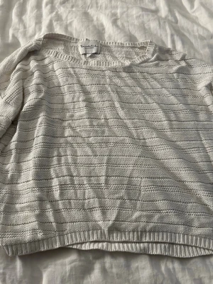 Vit stickad tröja från Bondelid - Vit stickad tröja från Bondelid med diskret horisontellt mönster. Tröjan har rund halsringning, långa ärmar och ribbade muddar vid ärmslut och nederkant. Perfekt för lager på lager och enkel att matcha till olika outfits.