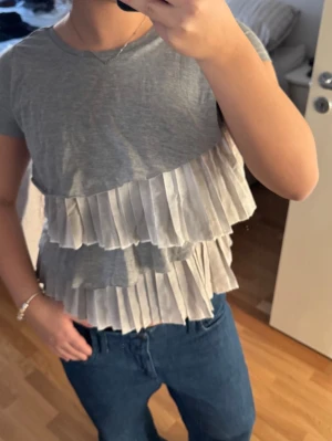 Grå volangtop från Rinascimento - Supersöt grå topp från Rinascimento med två lager vita volanger framtill. Storlek S 