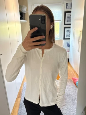 Vit basic kofta med knappar - En enkel och stilren vit kofta med rund halsringning och knappar framtill. 