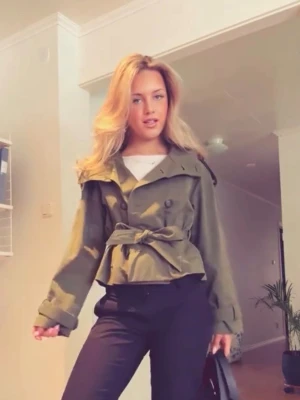 Gina trenchcoat  - Snygg kort trenchcoat i olivgrön. Jackan har ett matchande knytskärp i midjan. Säljer pågrund av att den inte passar mig, prislapp å allt e kvar. Men annars en sååå fin ”kappa”. Pris kan diskuteras💞