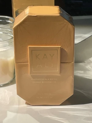 Kayali Marrakesh Orange Blossom EdP - Upptäck Kayali Marrakesh In A Bottle Orange Blossom 24, en lyxig parfym i en elegant, oktagonal glasflaska med guldtonad vätska. Doften har inslag av apelsinblom, kryddor och blommiga noter. Perfekt för dig som vill ha en unik och fräsch signaturdoft.