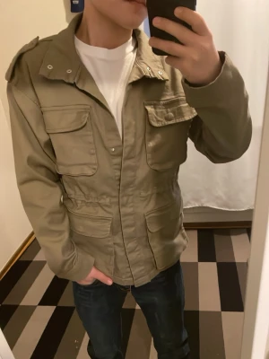 Fieldjacket  - Snygg grön fieldjacket i nyskick säljer då den sitter lite stor på mig skulle säga att den passar dig som är 165-170 om du vill att den ska sitta slim. Rekommenderar den starkt då den är skit trändig till våren och passar till i princip allt. Färgen ser bättre ut i bra ljus. 