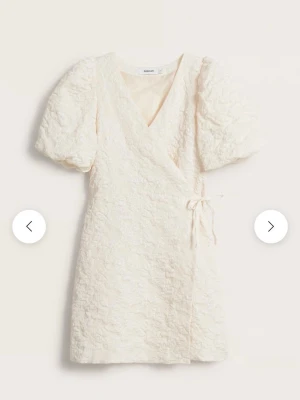 Vit omlottklänning/Studentklänning - Supersöt vit oanvänd kortklänning från Kappahl med puffärmar och omlottdesign. Klänningen har strukturmönstrad yta, v-ringning och knyt i sidan för en snygg siluett. Klänningen har även super smidiga fickor! Perfekt som studentklänning eller för sommarens alla tillfällen! Köpt för 899kr säljs för 450kr🌸🌸🌸