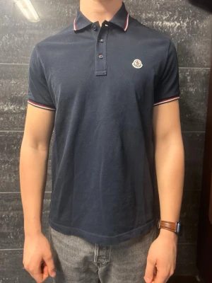 Moncler piké  - Super snygg marinblå Moncler piké i mycket bar skick! Knappt använd! 9/10! Modellen är 186 cm och väger 82 kg, såklart äkta ✅