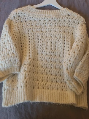 Vit stickad tröja från Zara - Mysig vit stickad tröja från Zara med hålmönster och breda ribbade muddar. Tröjan har rund halsringning och ballongärmar. 