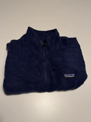 Patagonia fleecejacka 1/4 zip, mörkblå, L, Unisex  - Mysig mörkblå fleecejacka från Patagonia med halv dragkedja och hög krage. Jackan har en enkel design med liten logga på bröstet och är tillverkad i mjuk fleece som håller dig varm under kyliga dagar.