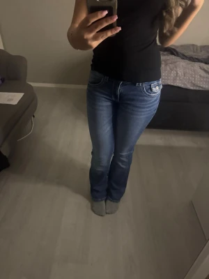 Blå bootcut jeans med vita sömmar - Snygga blå bootcut jeans med kontrasterande vita sömmar och klassisk femficksdesign. Jeansen har en något utsvängd passform nedtill och sitter tajt över låren. De är från Gina Young och är i storlek 164 men jag är 160 cm och bär storlek 34-36 i jeans och dessa passar perfekt. Använda ett fåtal gånger.