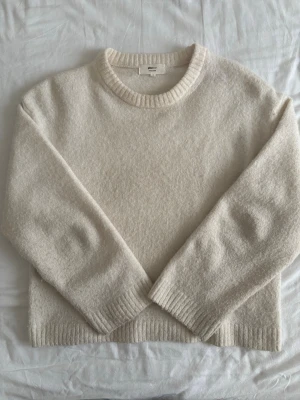 Gräddvit stickad tröja  - Mysig gräddvit stickad tröja från Gina Tricot med rund halsringning och ribbade muddar vid ärmslut och nederkant. Perfekt för lager på lager och enkel att matcha med allt. Klassisk och stilren design.