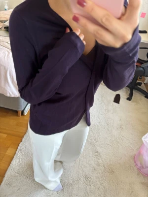 Lila omlottkofta med långa ärmar - Snygg lila omlottkofta med långa ärmar och avslappnad passform. Perfekt att slänga över en topp för en chill och stilren look. Koftan har en djup v-ringning och mjukt material som känns skönt mot huden.