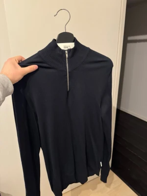 Svart halvzip-tröja - Stilren svart långärmad tröja med halv dragkedja och hög krage. Perfekt för lager-på-lager och enkel att matcha med olika outfits. Tröjan är i ett mjukt och tunt material som känns skönt mot huden. 