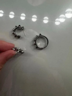 Silvriga örhängen med nitar, Edblad - Coola silvriga örhängen i ringmodell med utstickande nitar runt om. De har en edgy och modern design som passar perfekt för dig som gillar att sticka ut. Materialet ser ut att vara metall och de har en enkel stängning.