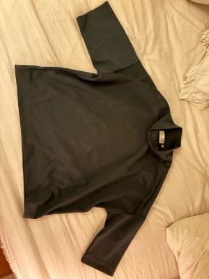 Mossgrön polotröja från Carin Wester - Minimalistisk svart polotröja från Carin Wester med trekvartsärmar. 