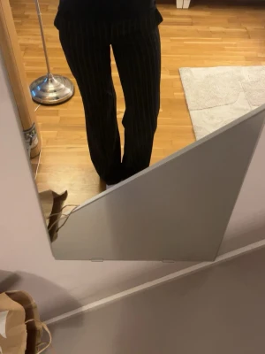 Randiga kostymbyxor från Bik Bok - Säljer ett par svarta kostymbyxor från Bik Bok med tunna vita vertikala ränder. Byxorna har raka ben, bälteshällor och stängs med hake och dragkedja. Perfekta för en stilren och trendig look. Använda 2 ggr.