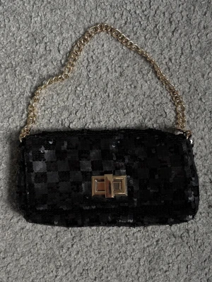 Handväska - Snygg svart handväska täckt av glittrande paljetter och med en guldfärgad kedja som axelrem🖤 Priset är diskuterbart vid snabb affär🥰 