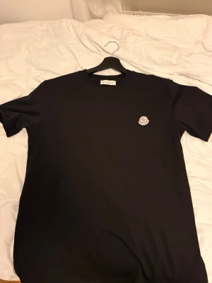 Svart Moncler t-shirt med logga - Snygg svart t-shirt från Moncler med klassisk rund hals och Moncler-logga broderad på bröstet. Enkel och stilren design som passar till det mesta. Tillverkad i mjuk bomull för skön känsla hela dagen.