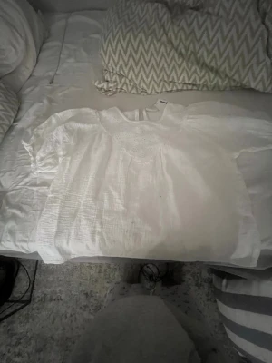 Vit blus med broderad detalj - Jättefin blus från Kappahl. Den har detaljer fram och där bak stänger man ned en knap. Jättebra skick.