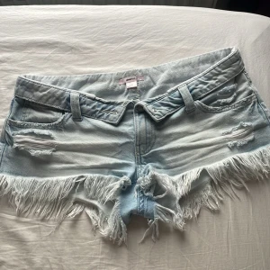 Ljusblå jeansshorts från Gina - Snygga ljusblå jeansshorts från Gina 14+!🩵Pris kan diskuteras! Shortsen har snygga detaljer och fransig kant nertill. Perfekta för sommaren!