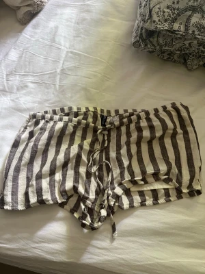 Linneshorts - Brun, vit randiga linne shorts med fickor fram, lågmidjade. Säljer då dom inte passade 