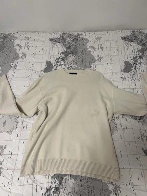 Beige stickad tröja med rund hals - En stilren beige stickad tröja med rund halsringning och långa ärmar. Tröjan har ribbstickade muddar vid ärmslut och nederkant, vilket ger en snygg och enkel look. Perfekt för lager-på-lager och passar till det mesta.