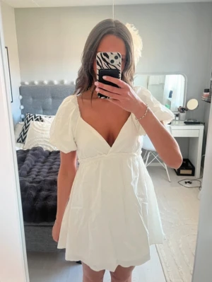 Vit kortklänning med puffärmar - Säljer nu denna söta vita kortklänning med puffiga kortärmar och v-ringning. Perfekt för student eller sommaren! 💕aldrig använd och prislappen är kvar! ☺️