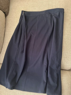 Marinblå omlottkjol med bälte - Stilren omlottkjol med bälte i midjan. Kjolen har en enkel design och är perfekt för dig som gillar minimalistisk stil. Passar till många olika outfits och är lätt att matcha med både toppar och tröjor.