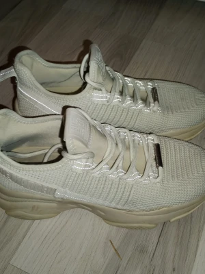 Beige  STEVE MADDEN sneakers med stickad ovandel - Steve Madden sneakers i beige med stickad ovandel och tjock sula. Skorna har reflekterande detaljer på snörningen och sidan samt dragflik bak. Perfekta för en trendig streetstyle-look.  1de är i kanon skick knappt använda alls. Storlek 40:- .