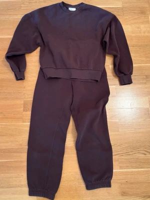 Brunt loungewear-set från Gina Tricot  - Mysigt tvådelat loungewear-set i brun färg från Gina Tricot. Setet består av en sweatshirt med rund hals och ribbade muddar samt matchande byxor med resår i midja och benslut. Perfekt för chill dagar hemma.