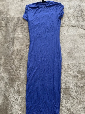 Blå långklänning från SHEIN  - En enkel och stilren blå långklänning från SHEIN. Klänningen har korta ärmar och rak passform, perfekt för dig som gillar minimalistisk stil. Tillverkad i mjukt material som känns skönt mot huden.
