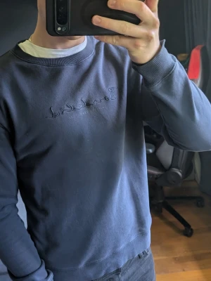 Mörkblå Bondelid sweatshirt - Mörkblå sweatshirt från Bondelid med broderad logga på bröstet. Tröjan har rund halsringning, ribbade muddar vid ärmslut och nederkant samt en avslappnad passform. Perfekt för en chill och stilren look.