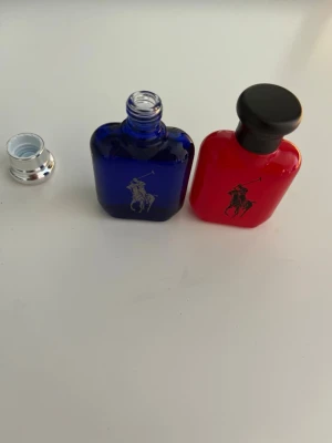 Ralph Lauren Polo parfymset - Säljer ett parfymset från Ralph Lauren Polo med två flaskor, en röd och en blå. Flaskorna är i glas med klassisk Polo-logga och har snygg, stilren design. Perfekt för dig som gillar exklusiva dofter och vill ha något som sticker ut i badrumsskåpet.