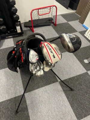 Komplett golfsett  - Golfset med flera klubbor från Callaway och Cobra. Inkluderar järn, driver, spoon och hybrid, samt en svart golfbag med röda detaljer och stativ. Skriv om frågor och pris kan diskuteras