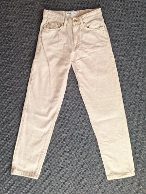 Jeans Bershka beige strl 34 - Snygga beiga jeans med rak passform och hög midja. Klassisk femficksmodell med knapp och dragkedja framtill. Perfekta att matcha med en crop top eller hoodie för en chill look.