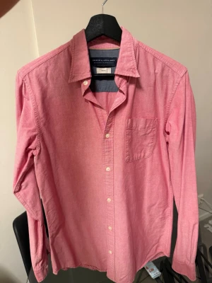 Rosa skjorta - Ros skjorta från Jack & jones med väldigt fin röd/rosa ton i verkligheten. Använts fåtal gånger.