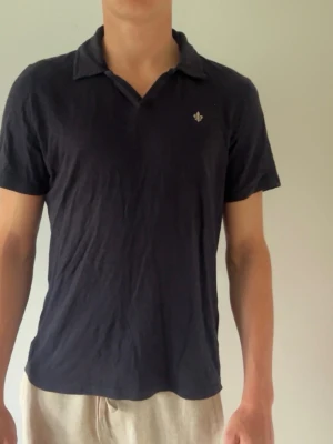 Mörk blå piké från Morris  - Klassisk mörkblå piké t-shirt med krage och liten broderad Morris  logga på bröstet. T-shirten har korta ärmar och normal passform, perfekt till jeans eller shorts. Tillverkad i mjuk bomull för skön känsla hela dagen.